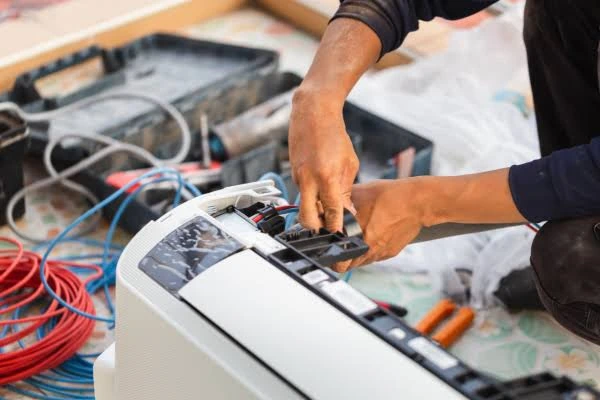 Hands servicing the internal components of an indoor air conditioning unit